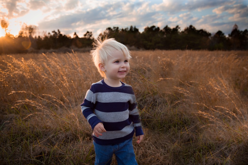 Child runs through grassy meadow in McGees Crossroads NC during a portrait session