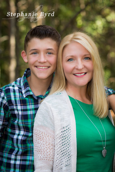 A teen boy puts his arm around his mom during an outdoor family portrait in Benson.