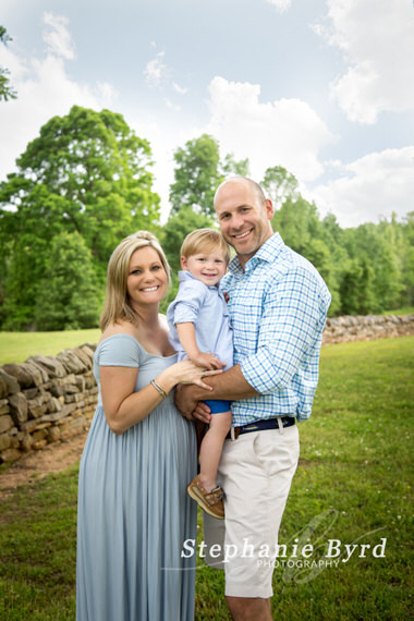 A family poses for outdoor photos next to a stone wall in Joyner Park.