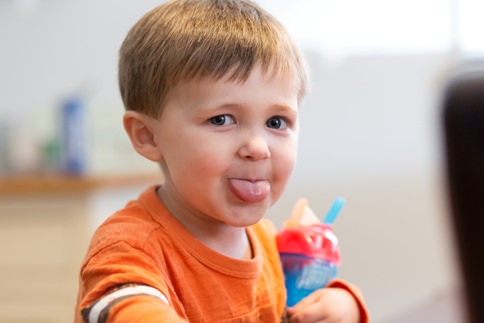 Toddler sticks his tongue out at mommy while getting family pictures